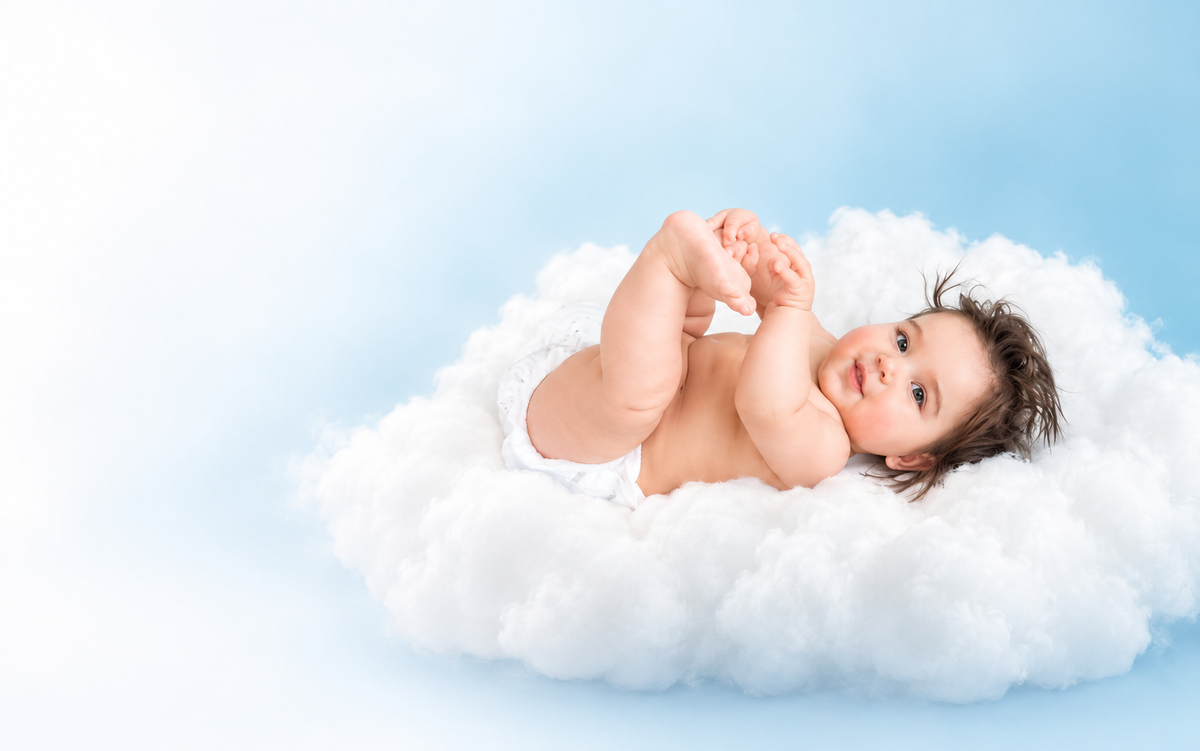 Baby lying on a soft white cloud against a bright blue background